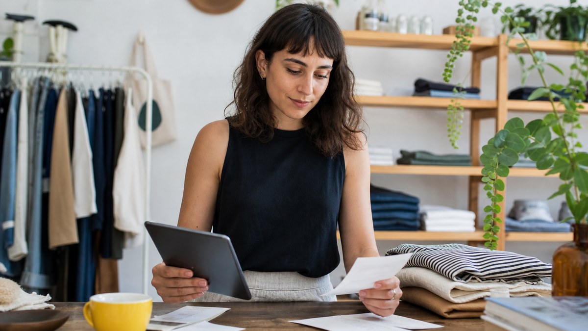 Small storefront owner reviewing receipts and a tablet at the shop counter